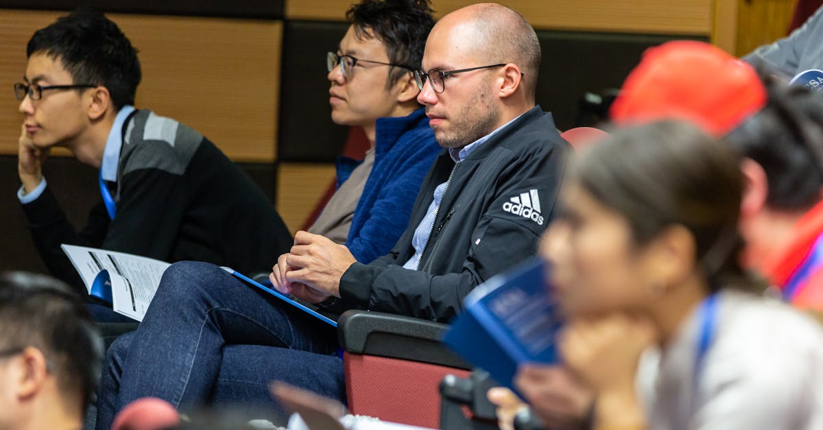 A diverse group of adults attentively listening to a lecture in an indoor conference setting.